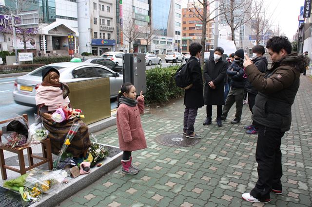 부산 동구 일본영사관 후문 근처 소녀상 앞에서 한 시민이 소녀상을 배경으로 한 딸의 모습을 사진에 담고 있다. 부산=연합뉴스