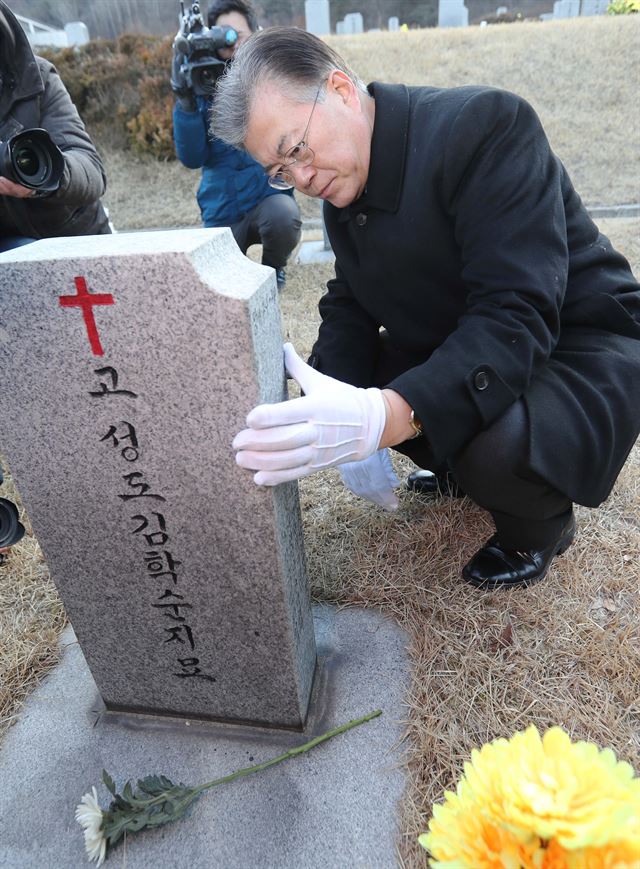 문재인 더불어민주당 전 대표가 11일 충남 천안시 망향의 동산에서 위안부 피해자 김학순 할머니 묘소에 헌화한 후 묘비를 어루만지고 있다. 연합뉴스