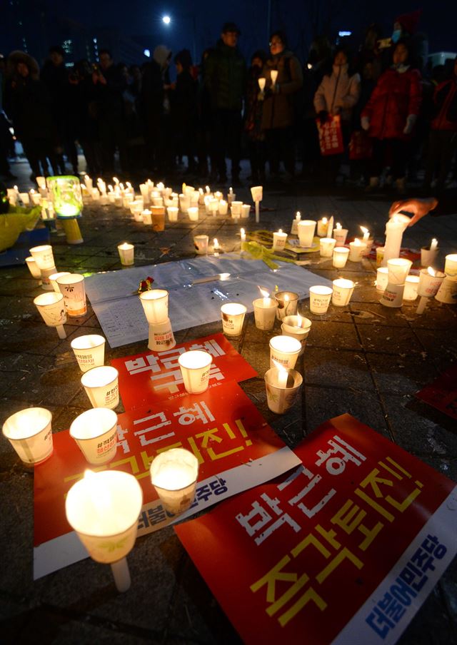 지난달 31일 서울 종로구 세종대로 광화문 광장에서 열린 박근혜 대통령 퇴진을 촉구하는 제10차 주말 촛불집회를 마친 시민들이 세월호 모형 앞에서 촛불을 밝히고 있다. 뉴시스