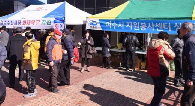 전남 여수수산시장 화재 복구 현장에서 자원봉사자들이 피해 상인들을 위로하며 지원에 나서고 있다.