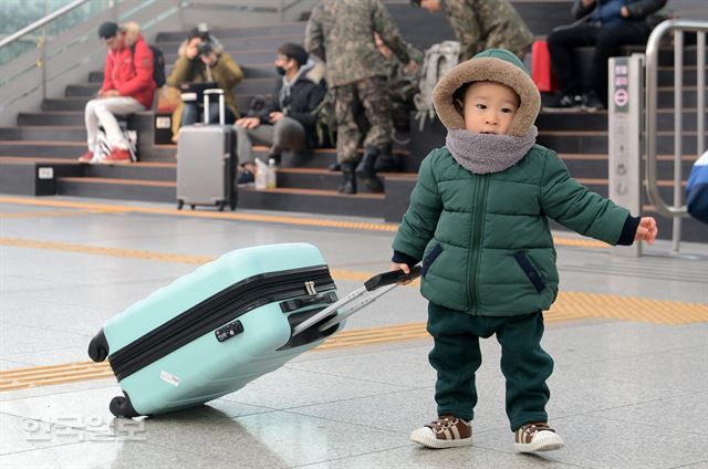 한 아이가 자기 덩치보다 큰 캐리어를 끌고 있다.