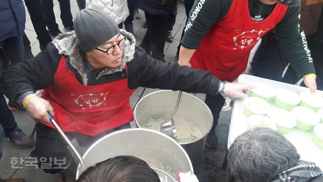 설날인 28일 서울 종로구 광화문광장에서 봉사모임 ‘평등사회를 위한 집밥’ 봉사자들이 시민들에게 떡국을 나눠주고 있다.