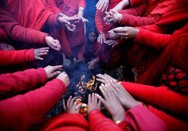 네팔 카트만두 부근에서 파나우티에서 30일(현지시간) 힌두축제 '스와스타니 브라타카타' 가 열린 가운데 트리베니 강변에서 축제를 마친 순례객들이 모닥불 앞에 둘러앉아 몸을 녹이고 있다. 로이터 뉴스1