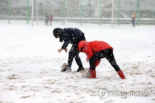 눈이 오고 있는 학교 운동장에서 학생들이 눈덩이를 굴리고 있다. 연합뉴스