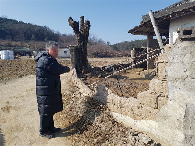 부지2리 박종헌 이장이 지진 피해가옥 담벼락을 가리키고 있다