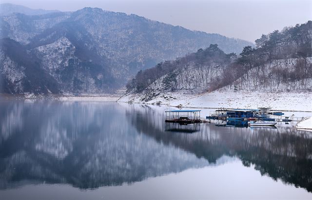 겨울 가뭄으로 물에 잠겨 있던 산에 붉은 속살이 드러나지만 휘날리는 희날리는 눈발과 물 위의 반영에 아름다운 풍경으로 변한다.