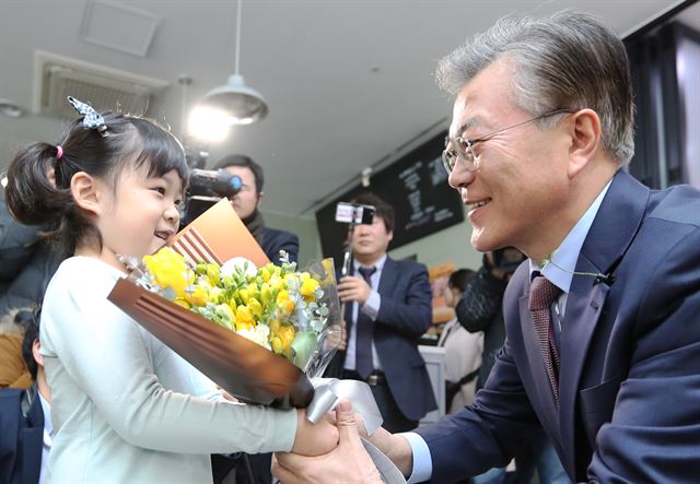 문재인 더불어민주당 전 대표가 7일 대전 서구 한 카페에서 뇌 병변 1급 장애아 김건우(10)군의 여동생에게서 꽃다발을 받고 있다. 문 전 대표는 어린이 재활병원 건립을 위한 '기적의 새싹 핀 달기'에도 동참했다. 대전=연합뉴스