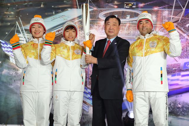 전 쇼트트랙 국가대표 변천사(왼쪽부터), 스피드스케이팅 유망주 김태완, 이희범 평창올림픽 조직위원장, 전 알파인 스키 국가대표 변종문 조직위 담당관이 9일 강릉하키센터에서 열린 '평창올림픽 G-1년 언론설명회'에서 성화봉과 성화봉송 유니폼을 입고 포즈를 취하고 있다. 평창 올림픽 조직위 제공