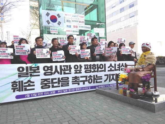 ‘소녀상을 지키는 부산시민행동’이 13일 오전 부산 동구 초량동 일본영사관 앞 소녀상 인근에서 기자회견을 열고 있다. 시민단체 회원들 뒤로 지하철 승강기 벽면에 30대 남성이 붙인 소녀상 철거 요구 부착물이 눈에 띈다.