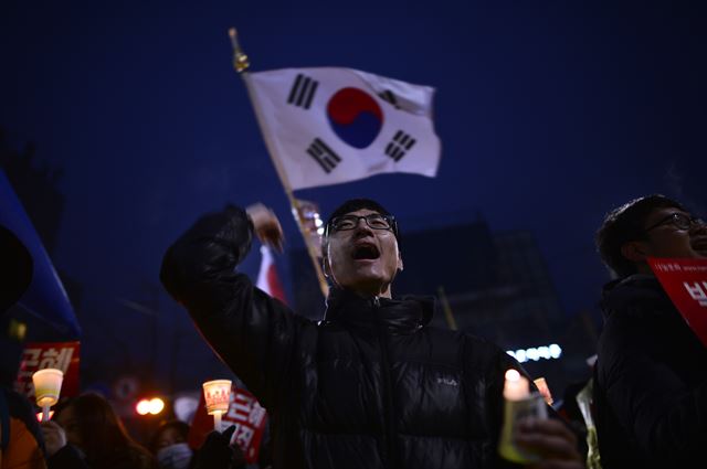 지난해 11월 26일 열린 촛불집회에서 박근혜 대통령 퇴진을 요구하며 행진하고 있는 참가자 뒤로 태극기가 펄럭이고 있다. 심현철 코리아타임즈 기자