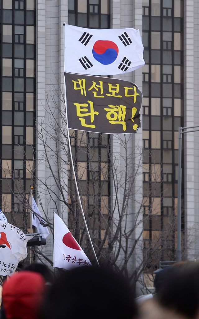 지난 11일 열린 촛불집회에서 대통령 탄핵을 요구하는 깃발 위로 태극기가 달려있다.