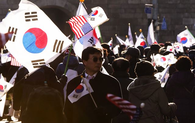 지난 11일 대통령 탄핵을 반대하는 보수단체 집회 참가자들이 태극기와 성조기를 들고 행진하고 있다.