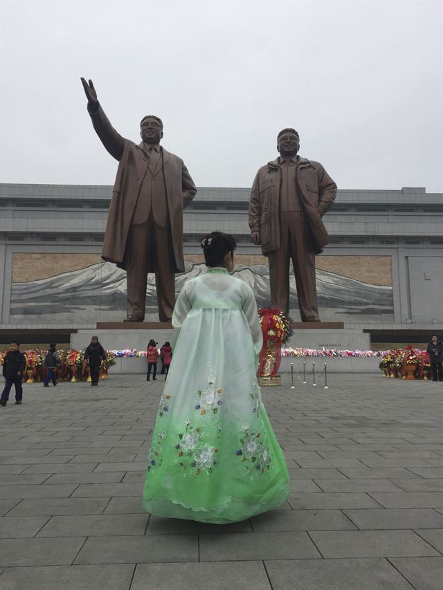 김정은 국무위원장의 이복형 김정남이 피살된 지 나흘 째를 맞았으나 북한 당국이 침묵하고 있는 가운데 김정일 생일(광명성절) 75돌을 맞은 16일(현지시간) 평양에서 한복을 곱게 차려 입은 한 주민이 기일성과 김정일 동상이 있는 만수대 언덕을 방문하고 있다. AP 연합뉴스