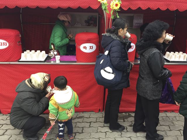 김정은 국무위원장의 이복형 김정남이 피살된 지 나흘 째를 맞았으나 북한 당국이 침묵하고 있는 가운데 김정일 생일(광명성절) 75돌을 맞은 16일(현지시간) 평양에서 주민들이 차판매대 앞에서 뜨거운 음료를 마시고 있다. AP 연합뉴스