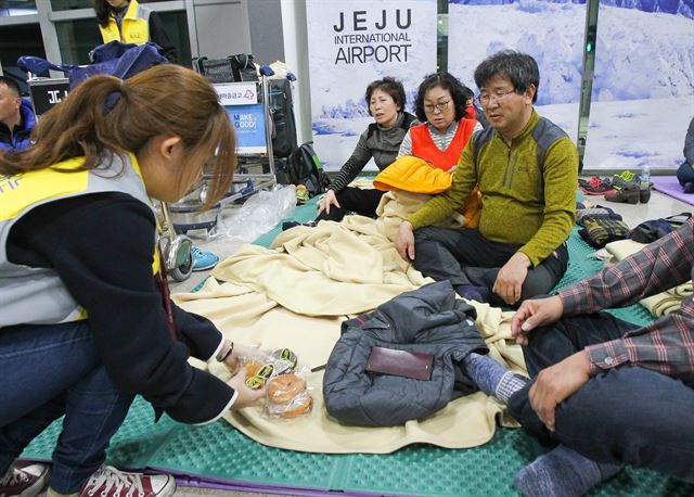 19일 오후 제주국제공항 2층 대합실에 강풍과 난기류로 인한 항공기 결항으로 제주를 떠나지 못하게 된 체류객들이 공항에서 나눠주는 빵을 지급받고 있다. 뉴시스