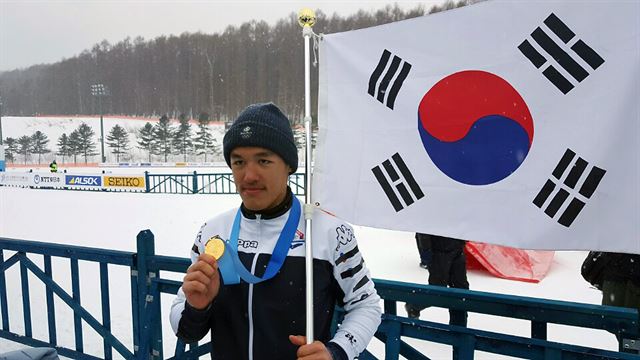 김 마그너스가 20일 일본 홋카이도 삿포로의 시라하타야마 오픈 스타디움에서 열린 삿포로 동계아시안게임 스키 남자 크로스컨트리 1.4㎞ 개인 스프린트 클래식 결선에서 3분11초40으로 우승한 후 태극기를 든 채 목에 건 금메달을 들어 보이고 있다. 대한스키협회 제공