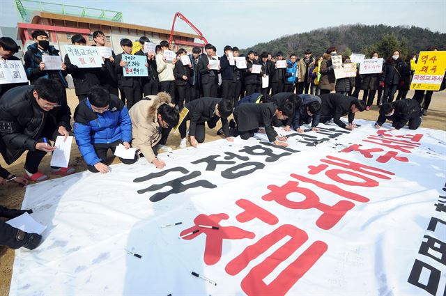 23일 오전 국정 역사교과서 연구학교로 지정된 경북 경산 문명고 학생과 학부모들이 국정교과서 철회를 요구하며 플래카드에 서명하고 있다. 뉴스1