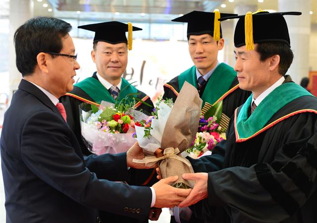 충북도농업기술원 차선세(맨 왼쪽)원장이 22일 충북대학교 대학원 학위수여식에서 동시에 박사학위를 취득한 연구직 3명(오른쪽부터 정재현·김선국·이재선)에게 화환을 전달하고 있다. 충북도농업기술원 제공