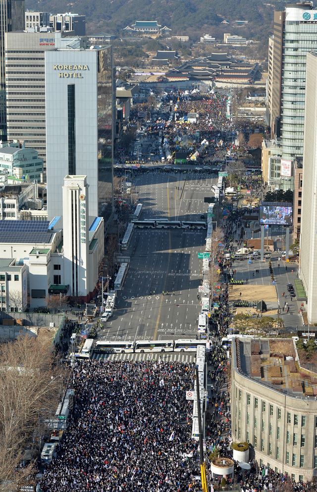 서울 광화문광장(위)에서의 박근혜정권 퇴진비상국민행동 등 시민단체와 시민들이 대통령 탄핵 촉구 집회를 열고 있다. 같은 시간 경찰 버스를 사이에 두고 대통령 탄핵기각을위한 국민총궐기운동본부가 서울광장에서 14차 탄핵반대 집회를 열고 있다. 두 집회 공간 사이에는 경찰이 참가자의 충돌을 방지하기 위해 차벽을 세우면서 일정 공간이 비어있다. 사진공동취재단