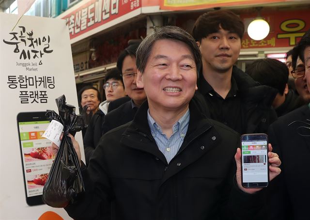 국민의당 안철수 전 공동상임대표가 26일 오후 서울 광진구 중곡제일골목시장을 방문, 휴대전화의 통합마케팅 플랫폼을 이용해 돼지고기를 구매하고 있다. 연합뉴스