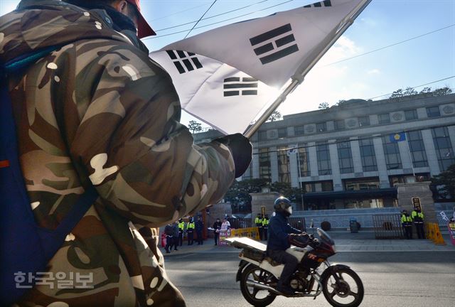 대통령 탄핵심판 공개변론이 열린 24일, 서울 종로구 재동 헌법재판소 앞에서 군복을 입은 한 시민이 태극기를 들고 서 있다. 서재훈기자