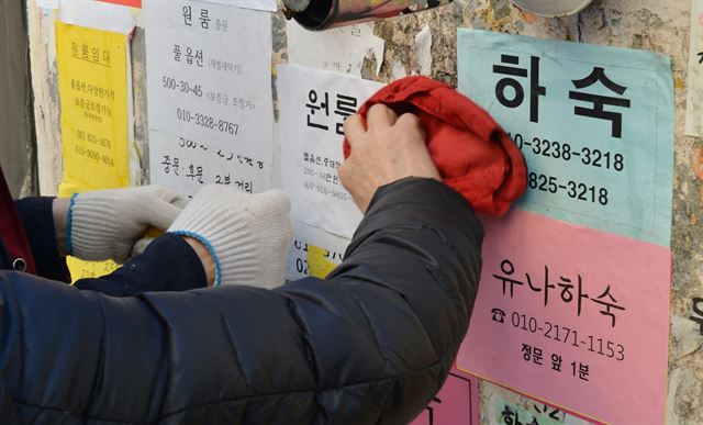 지난달 27일 흑석동 중앙대학교 부근에서 한 임대업자 부부가 담벼락에 빈 방 광고 전단을 붙이고 있다.