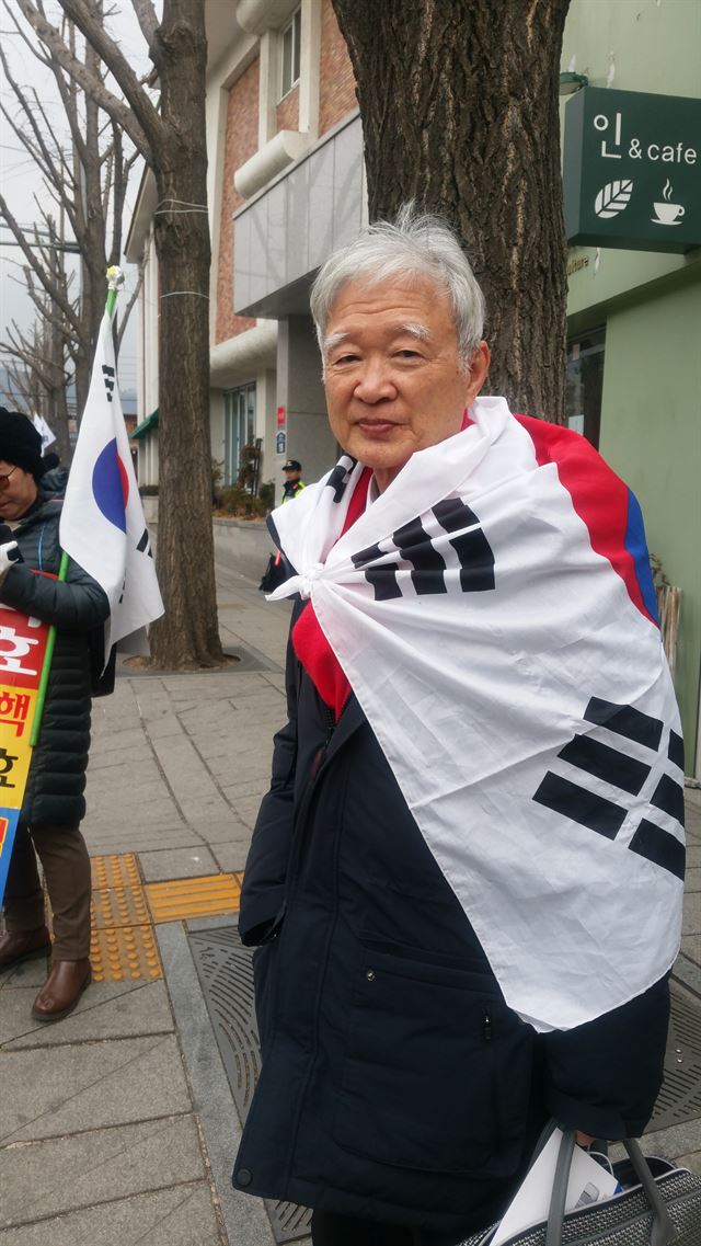 서석구 변호사가 지난달 16일 태극기를 두른 채 제14차 변론기일에 참석하기 위해 서울 재동 헌법재판소로 향하고 있다. 그는 태극기를 두른 이유를 묻자 “팬서비스예요”라고 답했다. 한국일보 자료사진