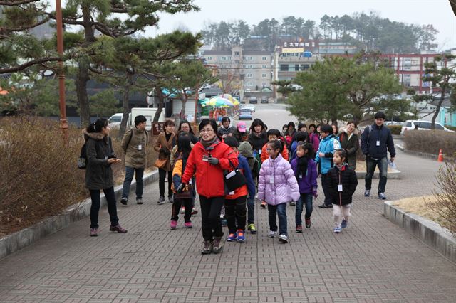 백제문화 체험에 나선 관광객들이 문화해설사의 설명을 들으며 관광지를 돌아보고 있다. 부여군 제공