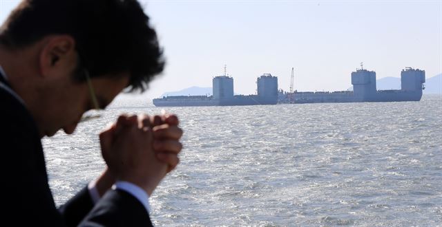 15일 오후 전남 진도군 세월호 참사 해역에서 해저에 가라앉아 있는 세월호를 끌어올리는 역할을 하는 잭킹바지 두 척에서 인양업체 직원들이 인양작업을 하고 있다. 두 바지선 사이로 세월호가 인양시 모습을 드러낸다. 해양수산부는 오는 21일 소조기에 테스트를 거쳐 다음 달 5일 소조기에는 기상 여건만 허락한다면 세월호 인양을 시도할 수 있을 것으로 내다봤다. 2017.3.15 진도=연합뉴스