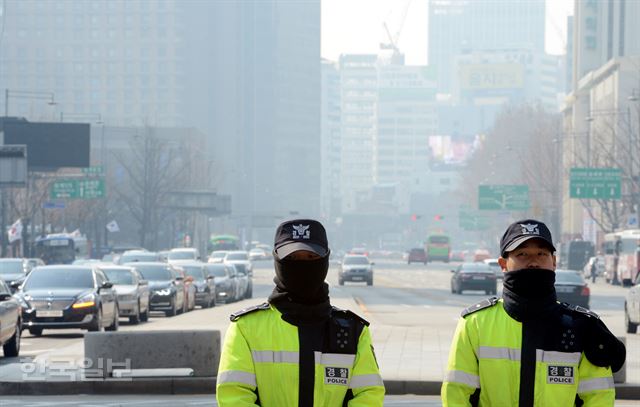 서울 시내 대기상태가 미세먼지 기준치를 초과한 17일 오전 서울 광화문사거리에서 경찰이 얼굴을 가린 채 경비를 서고 있다. 홍인기 기자