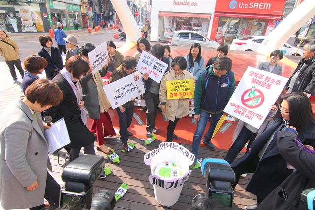 시민단체와 여성단체가 금복주 불매운동을 선언 후 금복주 술병 모형을 밟는 퍼포먼스를 하고 있다. 김민규기자 whitekmg@hankookilbo.com