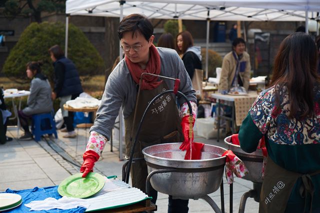 장터 한구석의 간이 개수대에서 자원봉사자가 설거지를 하고 있다. 마르쉐@ 제공