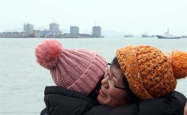 24일 오후 전남 진도군 세월호 참사 해역에서 미수습자 가족들이 인양된 세월호가 이동 준비하는 모습에 감격하며 포옹하고 있다. 연합뉴스