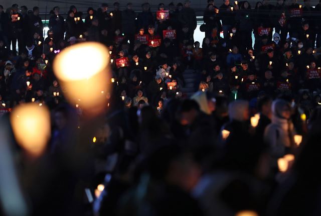 25일 오후 서울 종로구 광화문광장에서 열린 ‘21차 범국민행동의 날’ 촛불집회에서 참가자들이 박근혜 전 대통령 구속과 세월호 진상 규명 등을 촉구하며 촛불을 들고 있다. 연합뉴스