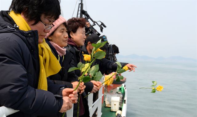 28일 오전 전남 진도군 세월호 사고해역 인근에서 열린 4대 종교 행사에서 미수습자 가족들이 온전한 수습을 기원하며 노란 장미꽃을 바다로 던지고 있다. 사진공동취재단 /2017-03-28(한국일보)