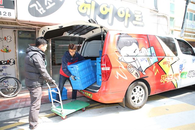 ‘지식도시락 배달’ 서비스를 전담하고 있는 관악구청 직원들이 29일 ‘번개 배달’이라고 씌여진 전용 차량에서 책을 내리고 있다. 관악구 제공