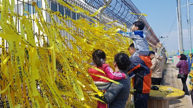 1일 목포신항을 찾은 한 가족이 추모 메시지를 담은 노란 리본을 달고 있다. 세월호가 목포신항에 접안한 뒤 첫 주말 가족단위 추모객들의 방문 행렬이 이어졌다. 목포=이상무 기자