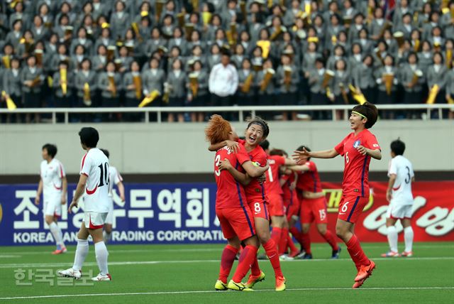 한국 선수들이 7일 평양 김일성경기장에서 열린 여자 아시안컵 예선 B조 2차전 북한과 경기에서 후반 30분 장슬기의 소중한 동점골이 터진 뒤 얼싸안으며 기뻐하고 있다. 허탈해하는 북한 선수들과 관중들의 모습도 보인다. 평양=서재훈 기자 spring@hankookilbo.com