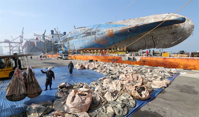 전남 목포신항에 접안해 있는 세월호에서 관계자들이 육상으로 펄이 담긴 자루를 옮기고 있다. 뉴스1