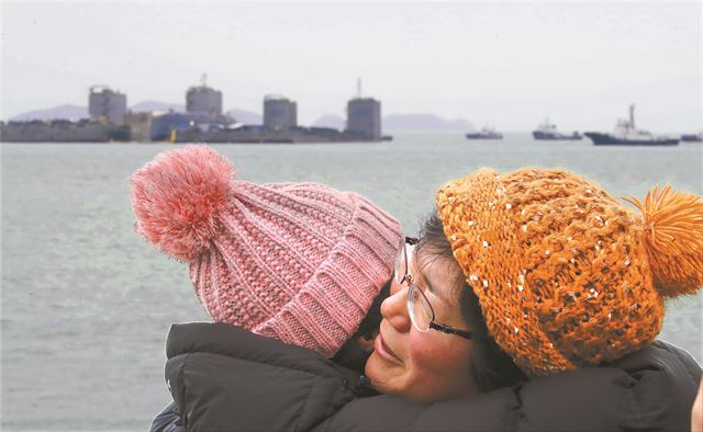 지난달 24일 오후 전남 진도군 사고 해역에서 세월호 미수습자 가족들이 인양된 세월호를 보고 감격하며 포옹하고 있다. 연합뉴스