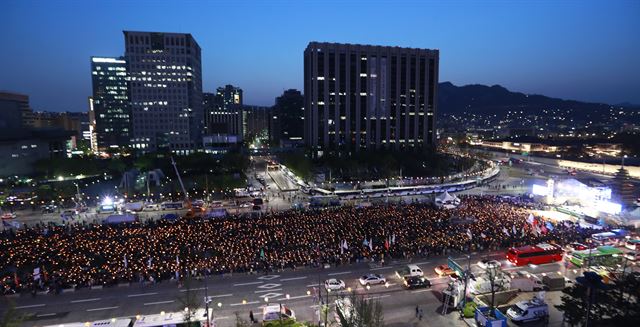 세월호 참사 3주기를 하루 앞둔 15일 서울 광화문광장에서 '박근혜정권퇴진 비상국민행동' 주최로 열린 '22차 범국민행동의 날' 촛불집회에서 참석자들이 촛불을 들고 있다. 연합뉴스