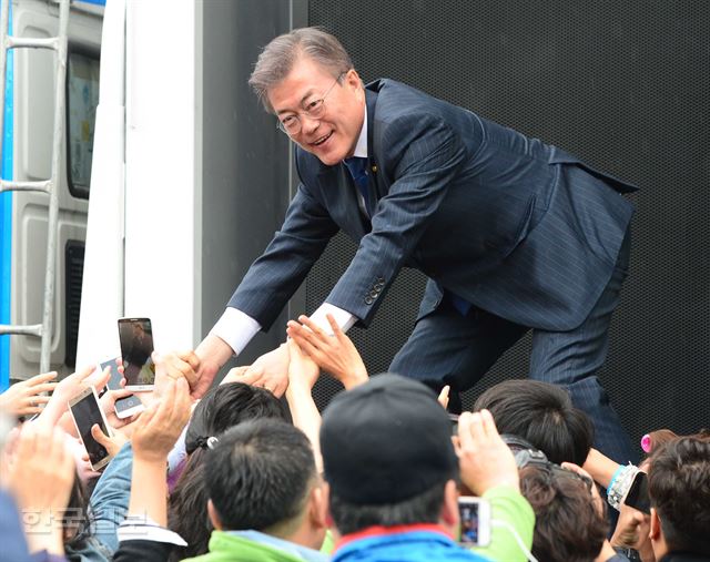 문재인 더불어민주당 대선후보가 17일 오전 대구 북구 산격동 경북대학교 북문 앞에서 첫 유세를 한 뒤 지지자들과 손을 잡고 있다. 오대근기자