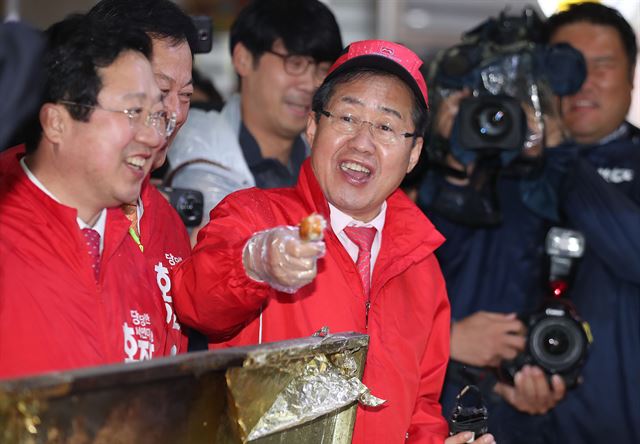 홍준표 자유한국당 대선후보가 17일 대전 중앙시장에서 상인들이 건네준 닭고기 구이를 건네며 크게 한 입 먹으라고 하자 너무 뜨겁다고 웃으며 하소연하고 있다. 대전=연합뉴스