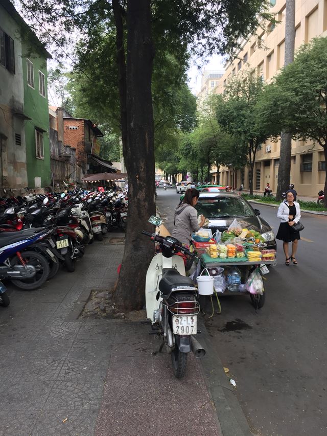 오토바이에 점령 당한 호찌민 시내 중심가 한 이면 도로변의 인도로. 보행자가 차도를 걷고 있다.