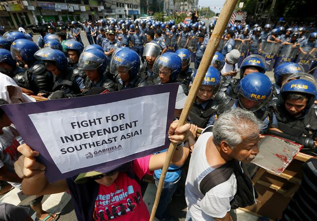 필리핀 마닐라에서 28일(현지시간) ASEAN 정상회담이 열리고 있는 가운데 미국대사관 부근에서 플래카드를 든 시위자들이 진압경찰 앞에 서 있다. AP 연합뉴스