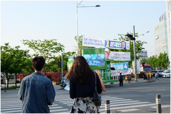 길가던 시민들이 30일 광주 충장로 대로변에서 각 당 대선 후보의 유세차와 플래카드를 바라보고 있다. 광주=손효숙 기자