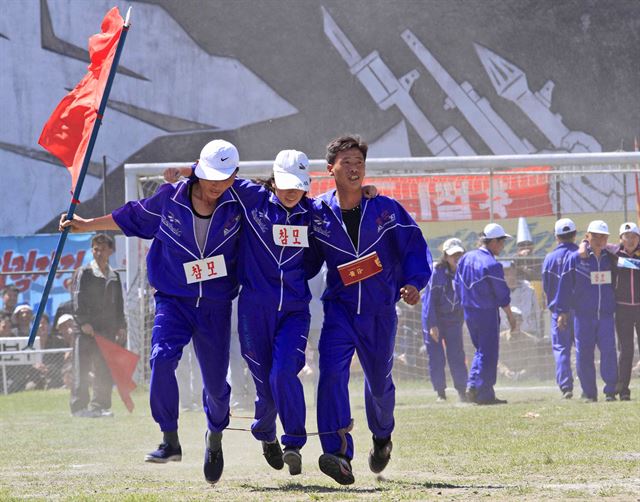 노동절을 맞은 1일(현지시간) 북한 평양의 평양 화력발전소에서 노동절 축하 행사가 열린 가운데 근로자들이 다리 묶고 달리기 경기를 하고 있다. AP 연합뉴스