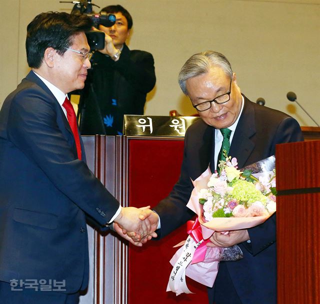 정우택(왼쪽) 자유한국당 원내대표가 3월 30일 국회에서 열린 의원총회에서 다음 날 전당대회를 끝으로 사퇴하는 인명진 비상대책위원장에게 꽃다발을 건넨 뒤 악수하고 있다. 배우한 기자