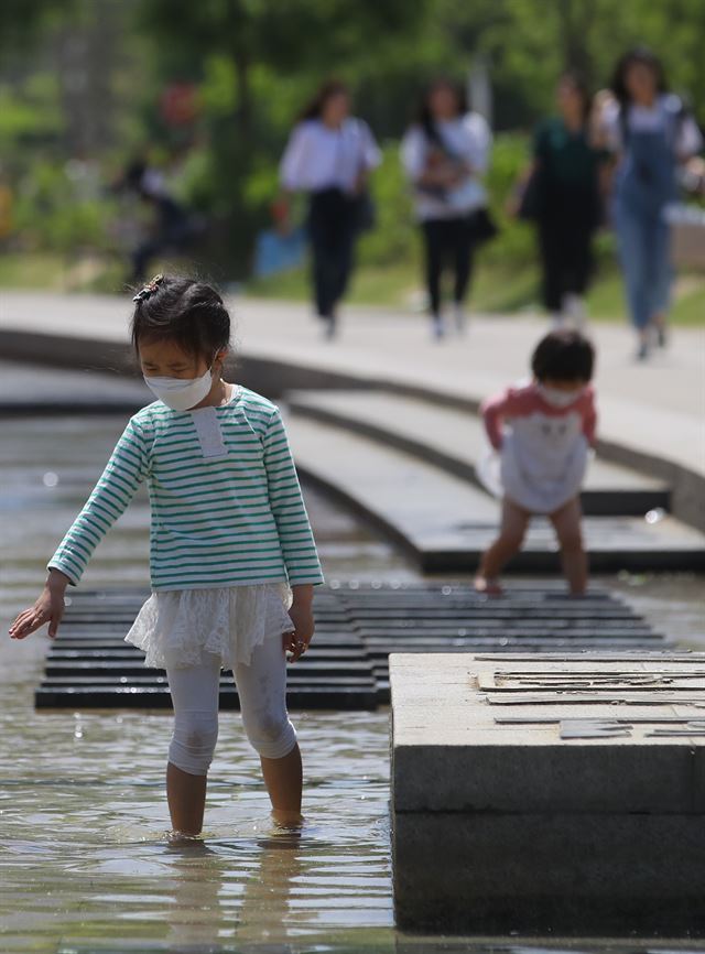 황금연휴 마지막 날이자 중국발 황사로 인한 미세먼지가 전국을 뒤덮은 7일 오전 서울 여의도 한강공원에서 어린이들이 마스크를 쓰고 물놀이를 하고 있다. 연합뉴스