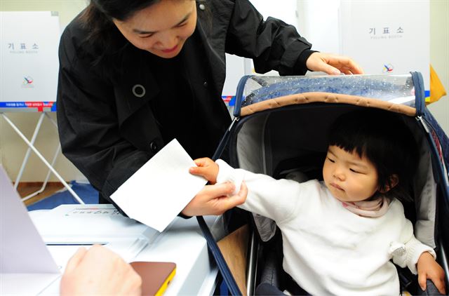 아이들을 꿈꾸게 할 미래는? 제19대 대통령선거일인 9일 오전 전북 전주시 서신동 동아한일아파트경로당에 마련된 제9투표소를 엄마와 함께 찾은 아이가 투표용지를 투표함에 넣고 있다. 뉴스1